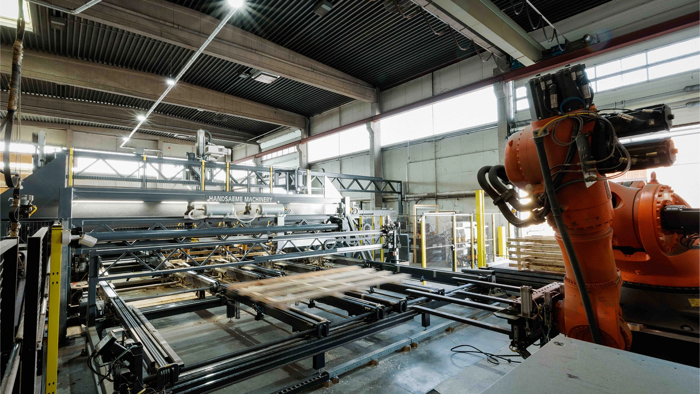 Automatisierte Palettenfertigungsmaschine mit Roboterarm in der Produktionshalle.