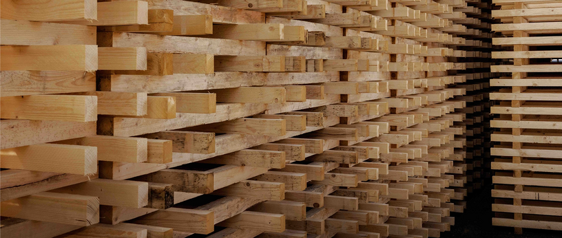 Side view of a high stack of wooden pallet boards.