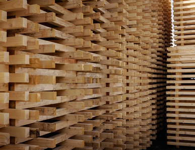 Side view of a high stack of wooden pallet boards.