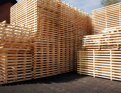 Große Stapel aus 2‑Wege-Holzpaletten auf dem Hof.