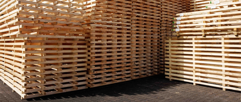 Große Stapel aus 2‑Wege-Holzpaletten auf dem Hof.