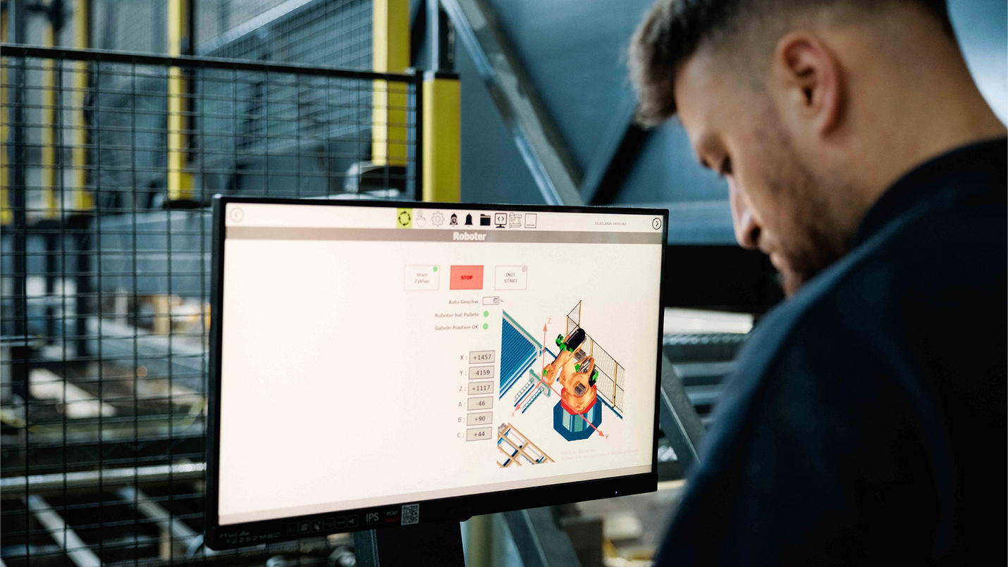 Mitarbeiter bedient das Terminal der Palettenfertigungsmaschine.