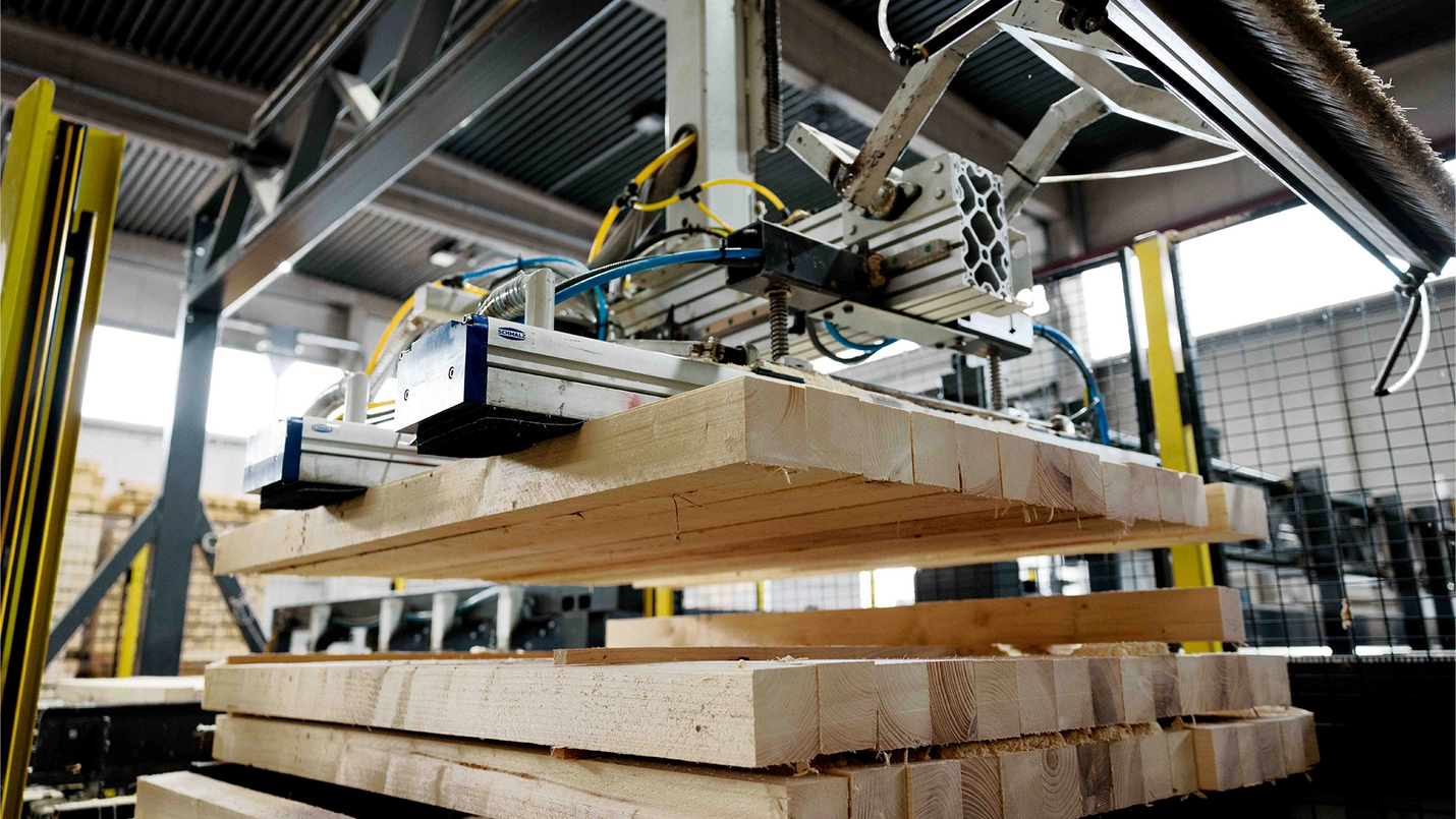 Palettenfertigungsmaschine greift Kanthölzer in der Produktionshalle.