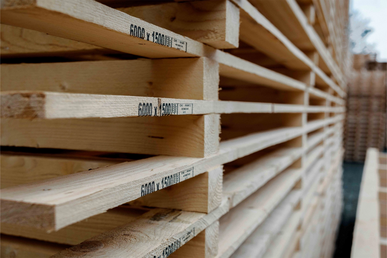 Detailansicht gestapelter Holzleisten mit Maßaufdruck.