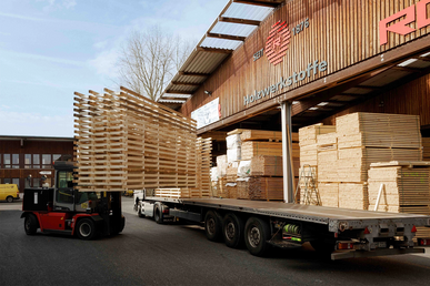 LKW wird mit gestapelten Holzpaletten beladen.