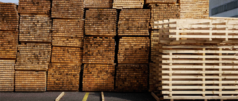 Stapel mit Holzbrettern und Palettenrahmen im Außenlager.