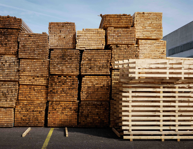 Stapel mit Holzbrettern und Palettenrahmen im Außenlager.