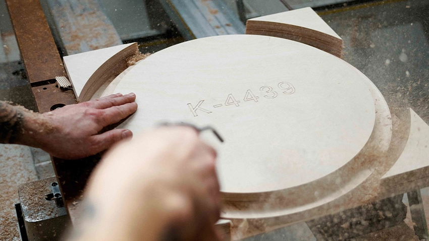 Rundes Holzteil wird auf der CNC bearbeitet, Späne fliegen.