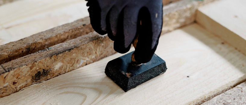 Hand stempelt Holzbrett auf einer Werkbank.